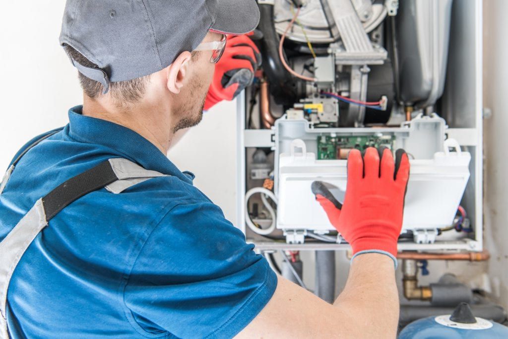 Technician performing a furnace maintenance tune-up on a high-efficiency furnace in Elwood, NY