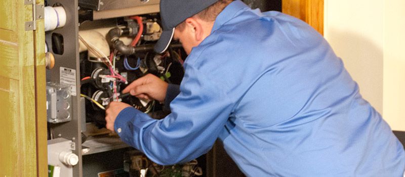 Heating technician repairing a furnace control system in Elwood, NY